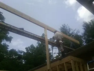 Carpenter setting a ridge beam over a new addition frame in Croydon