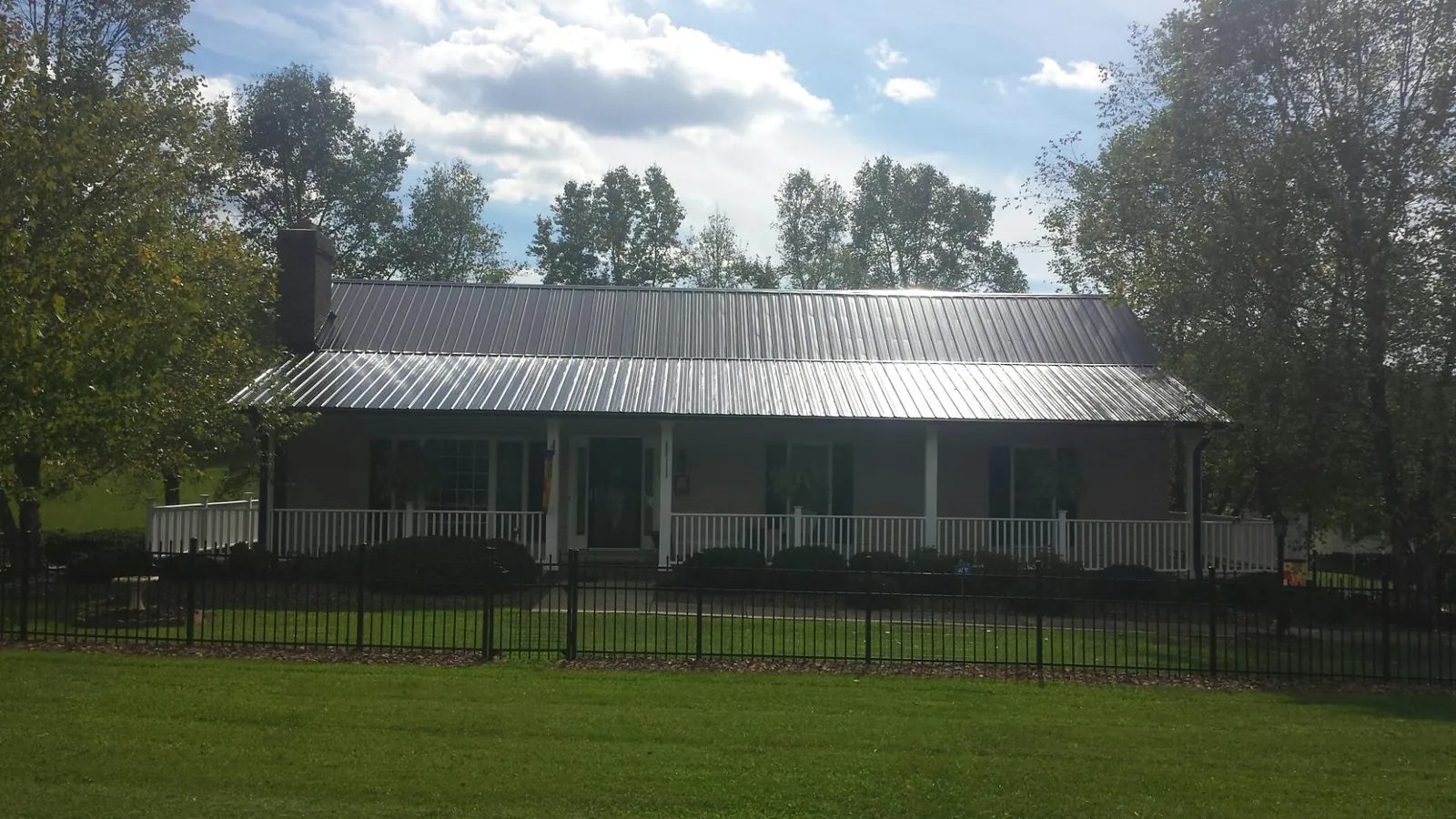 Gray metal roof on a brick ranch with a full width front porch — Gutter Guard Installation work by our crew in Croydon