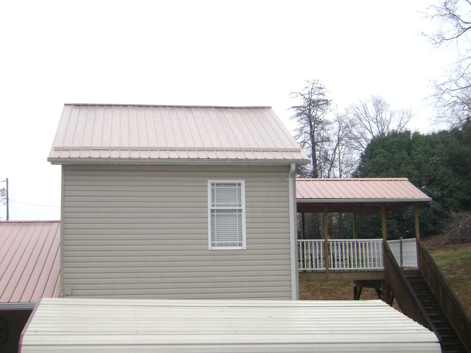 Tan metal roofs on a two story addition and attached porch, from a Roof Replacement job in Croydon